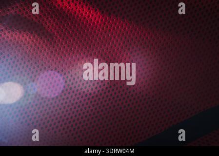 Rotes, technisches Mesh-Gewebe-Textur-Makro mit künstlerischem Linseneffekt und Bokeh-Hintergrund für Sportbekleidung und Sporttextilien Stockfoto