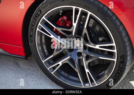 Nahaufnahme der Audi Alufelge mit vier Ringen Logo und Michelin Pilot Sport Reifen auf rotem Performance-Fahrzeug. Hochwertiges Automobildesign Stockfoto