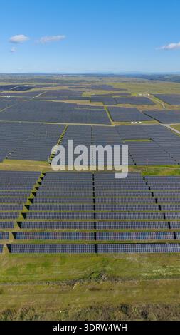 Aus der Vogelperspektive auf einen riesigen Solarpark, der sich über die Landschaft unter einem klaren blauen Himmel erstreckt, eine Energieoase, die in der Sonne schimmert, Cáceres, Cáceres España Stockfoto