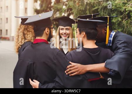 Gruppe von Absolventen, die während der Abschlussfeier gemeinsam im Freien feiern Stockfoto