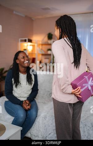 Tochter überrascht Mom mit einem Geschenk zu Hause Stockfoto