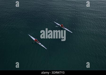 Aus der Vogelperspektive von zwei Kajaks, die durch das stille, dunkle Wasser schneiden und zarte Wellen erzeugen, die im Kontrast zu den weiten Weiten Mandurah und Western aus stehen Stockfoto