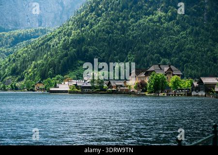 Malerisches österreichisches Dorf, eingebettet an einem ruhigen See mit üppig grünen Bergen im Hintergrund Stockfoto