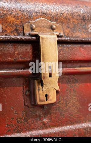 Nahaufnahme eines alten, rostigen Metallkastens und Schlüssellochs auf einem antiken roten Reisekoffer. Stockfoto