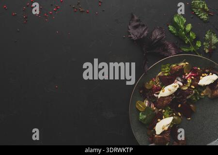 Sammlung frischer Salatgerichte auf dunkler Oberfläche mit verschiedenen Belägen und Kräutern Stockfoto