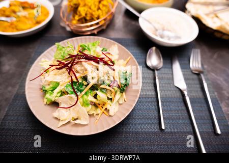 Indischer Gemüsesalat mit Gurke und Karotte auf Keramikplatte, serviert mit Reis- und Currygerichten im Restaurant Stockfoto