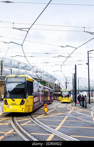 Zwei gelbe Metrolink-Straßenbahnen, die die Gleise vor dem modernen architektonischen Baldachin der Manchester Victoria Station befahren, aufgenommen am 18. Februar 2026. Stockfoto