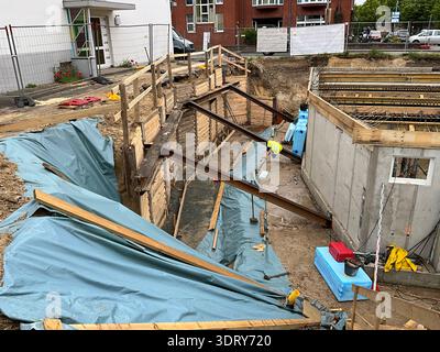 Tiefe Baugrube auf einer Wohnbaustelle mit Holzgerüst und Stahlträgern, die den umgebenden Boden stabilisieren. Verstärkter Concrre Stockfoto