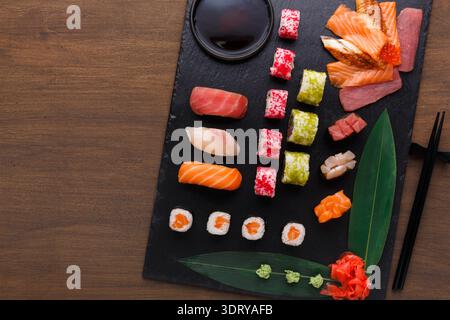 Sushi-Sammlung auf einem schwarzen Schieferbrett, organisiert für eine Mahlzeit Stockfoto