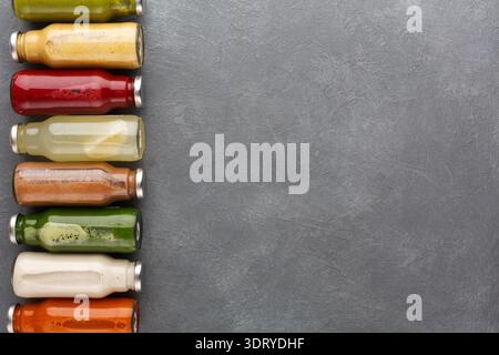 Flaschen mit buntem Saft, ordentlich auf einer grauen Oberfläche in einer Küche angeordnet Stockfoto