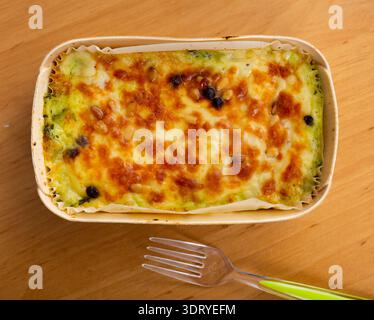 Auf dem Holztisch wird die Lasagne im Ofen unter Käsekruste gebacken Stockfoto