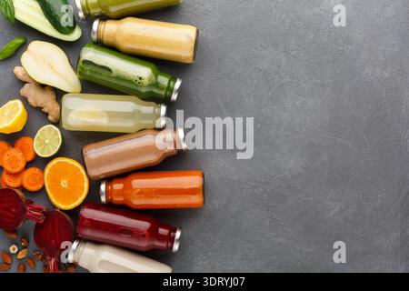 Verschiedene Arten frischer Säfte auf grauem Hintergrund mit Obst und Gemüse Stockfoto