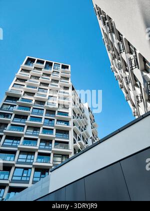 Moderne weiße Wohngebäude vor klarem blauem Himmel. Flache Aufnahme weißer Fassaden moderner Hochhausapartments mit Glasbalkonen. Stockfoto