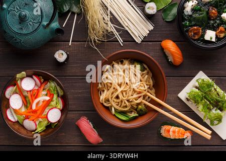 Auswahl an Gerichten mit Sushi, Nudeln und Salat auf Holztisch Stockfoto