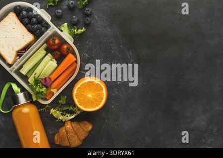 Sammlung gesunder Snacks in einer Lunchbox und farbenfrohen Früchten auf einem Tisch Stockfoto