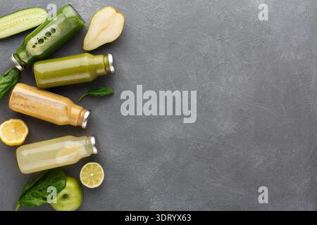 Frische Frucht- und Gemüsesäfte auf grauer Oberfläche mit Früchten und Grünpflanzen Stockfoto