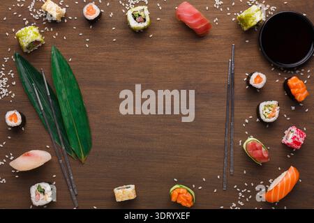 Sammlung von Sushi-Stücken auf Holzoberfläche mit Essstäbchen und Sojasauce Stockfoto
