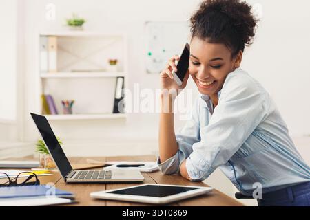 Frau, die tagsüber mit Laptop und Tablet am Schreibtisch arbeitet Stockfoto