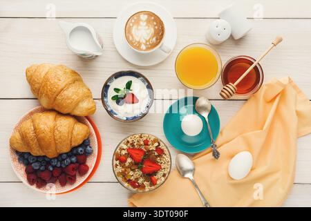 Frühstückskollage mit Croissants, Joghurt, Obst und Getränken auf einem Tisch Stockfoto
