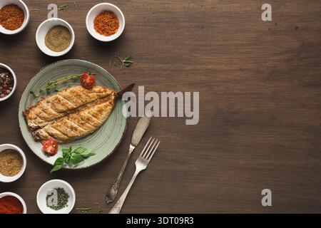 Collage aus Gewürzen und gegrilltem Fisch auf einem Holztisch mit Gewürzen in Schüsseln Stockfoto