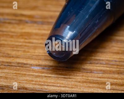 Optimierte Bildunterschrift (≤150 Zeichen): Makroaufnahme einer schwarzen Stiftspitze aus Kunststoff, die auf einer Holzoberfläche steht und Schrift, Kreativität und Bildung symbolisiert Stockfoto