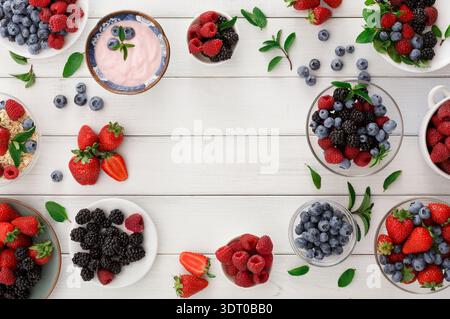 Sammlung von Beeren und Joghurt auf einem Tisch mit frischem Obst und Müsli Stockfoto