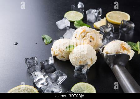 Zitroneneis auf dunkler Oberfläche mit Minze und Eiswürfeln im Hintergrund Stockfoto