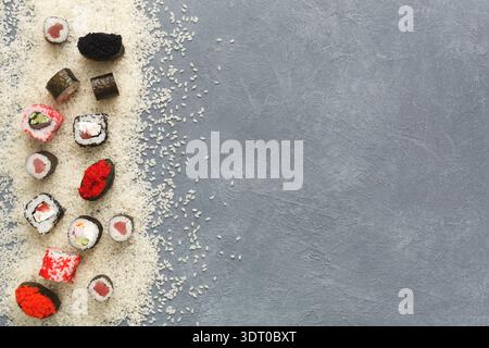 Bunte Sushi Rolls auf grauer Oberfläche mit weißem Reis Stockfoto