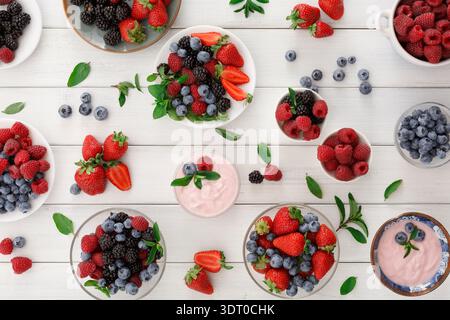 Frisches Obst und Joghurtschalen auf einem Holztisch für eine bunte Präsentation Stockfoto