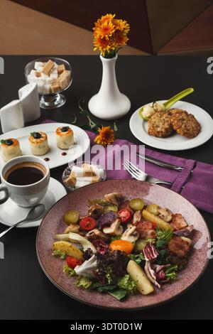 Sammlung von Gerichten auf einem Tisch mit Kaffee und Blumen, die während der Mahlzeit serviert werden Stockfoto