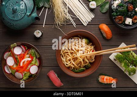 Sammlung verschiedener Gerichte und Getränke auf einer Holzfläche mit Stäbchen angeordnet Stockfoto