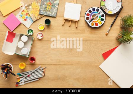 Sammlung von Kunstzubehör und Kreationen auf einem Holztisch in einem kreativen Arbeitsbereich Stockfoto