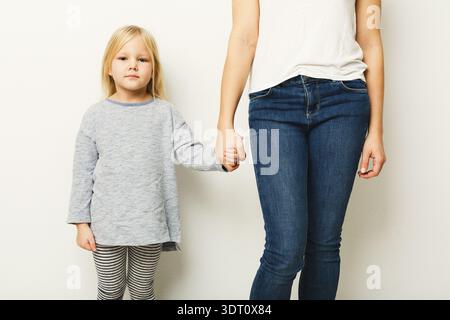 Kinder und Erwachsene halten die Hände in einer einfachen Umgebung mit einem schlichten weißen Hintergrund Stockfoto