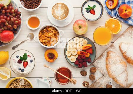 Frühstückssammlung mit Obst, Müsli und Getränken auf einem Holztisch am Morgen Stockfoto