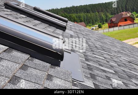 Nahaufnahme der Dachfenster-Reparatur mit Abdichtungsmembran auf Asphaltschindeldach. Dachkonstruktion. Stockfoto