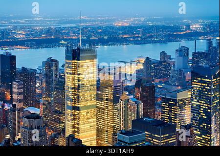 Die Skyline von Manhattan zeigt Gebäude und Lichter in der Abenddämmerung. Die Aussicht hebt den Fluss und die Stadtgestaltung hervor, wenn die Nacht näher rückt. Stockfoto