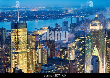 Blick auf Manhattan in der Abenddämmerung mit Stadtlichtern und Gebäuden entlang des Flusses. Der Himmel verdunkelt sich, wenn die Nacht über New York City herankommt. Stockfoto