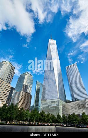 An klaren Tagen in Manhattan, New York, laufen die Menschen in der Nähe des National September 11 Memorial Museum und des One World Trade Center. Stockfoto