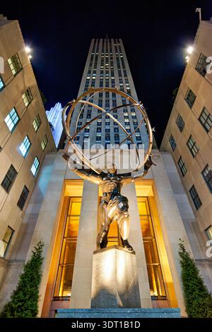 Eine Statue des Atlas steht hoch im Rockefeller Center in Manhattan. Die Szene zeigt die Statue, die nachts einen großen Globus hochhält. Stockfoto