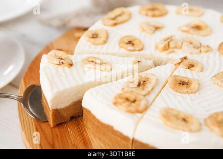 Köstliches Bananendessert auf Holzbrett mit Scheiben und Toppings Stockfoto