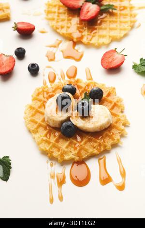 Köstliche Waffelcollage mit Früchten und Sirup auf einem einfachen Hintergrund Stockfoto