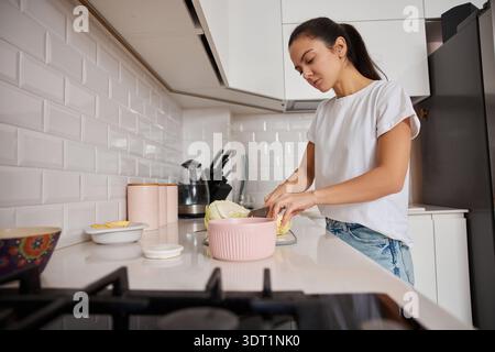 Frau, die Kohl auf einem Schneidebrett hackt und zu Hause eine gesunde Mahlzeit zubereitet Stockfoto