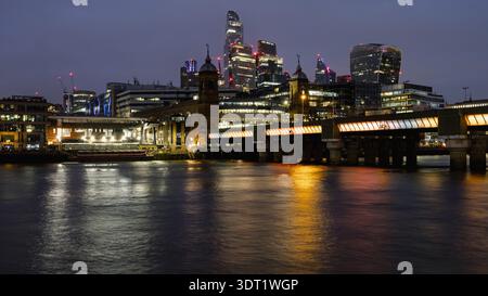 Atemberaubende Aussicht auf Londons Skyline, beleuchtet vor dem Dämmerungshimmel, mit modernen Wolkenkratzern und klassischer Architektur entlang des ruhigen Flusses Stockfoto
