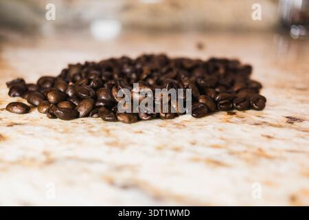 Eine Nahaufnahme von Kaffeebohnen auf einer Marmorarbeitsfläche, die das Wesen eines warmen Morgenrituals einfängt, perfekt für die Zubereitung des Frühstücks und Stockfoto