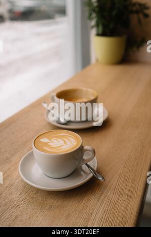 Zwei Tassen Kaffee auf dem Fenstertisch mit Schnee draußen Stockfoto