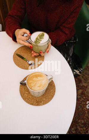Zwei Tassen Kaffee und Matcha Latte mit einem Freund am runden Tisch Stockfoto