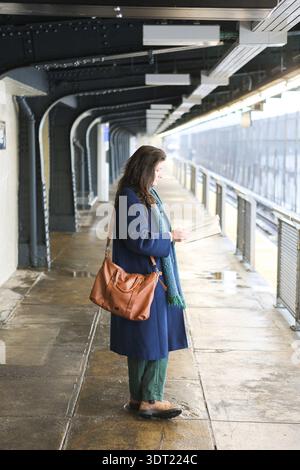 Millennial Woman liest Buch auf der U-Bahn-Plattform in Brooklyn Stockfoto