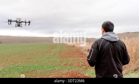 Eine landwirtschaftliche Drohne, die über bewässertes Weizenfeld in Alfambra, Teruel, fliegt. Verteilung von Stickstoffdünger mit Präzisionslandwirtschaftstechnologie un Stockfoto