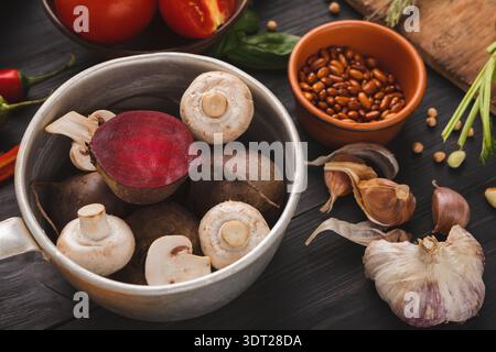 Sammlung von Gemüse und Gewürzen auf einem Holztisch mit einer Schüssel mit Pilzen und Rüben Stockfoto