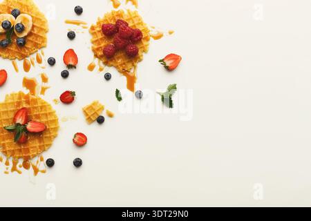 Waffelcollage mit Früchten und Sirup in einer Sammlung auf einem unkomplizierten Hintergrund Stockfoto